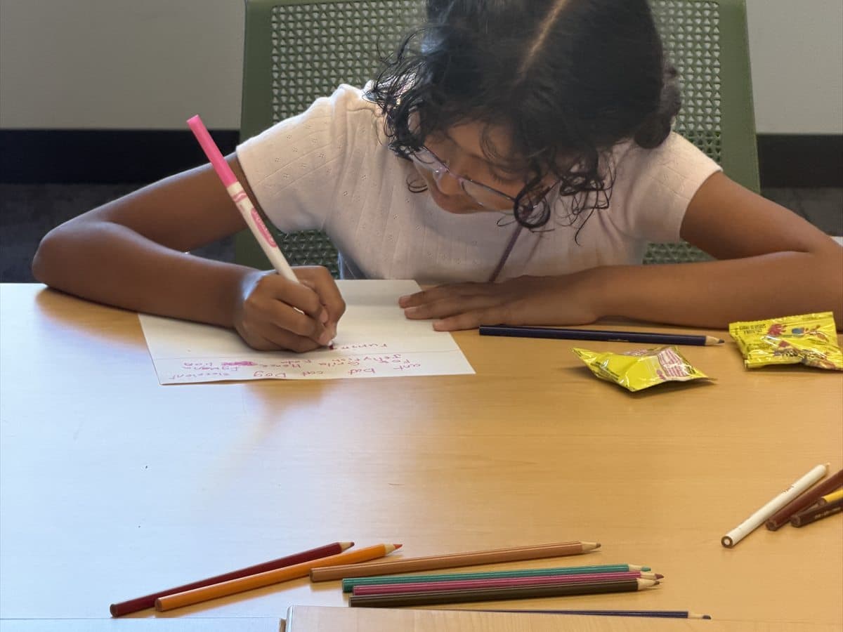 A child practicing focused writing at a classroom table.